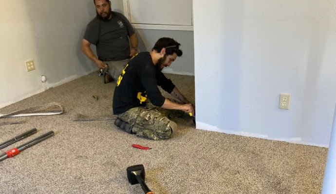 Two experts are working on remodeling a home and installing carpet.