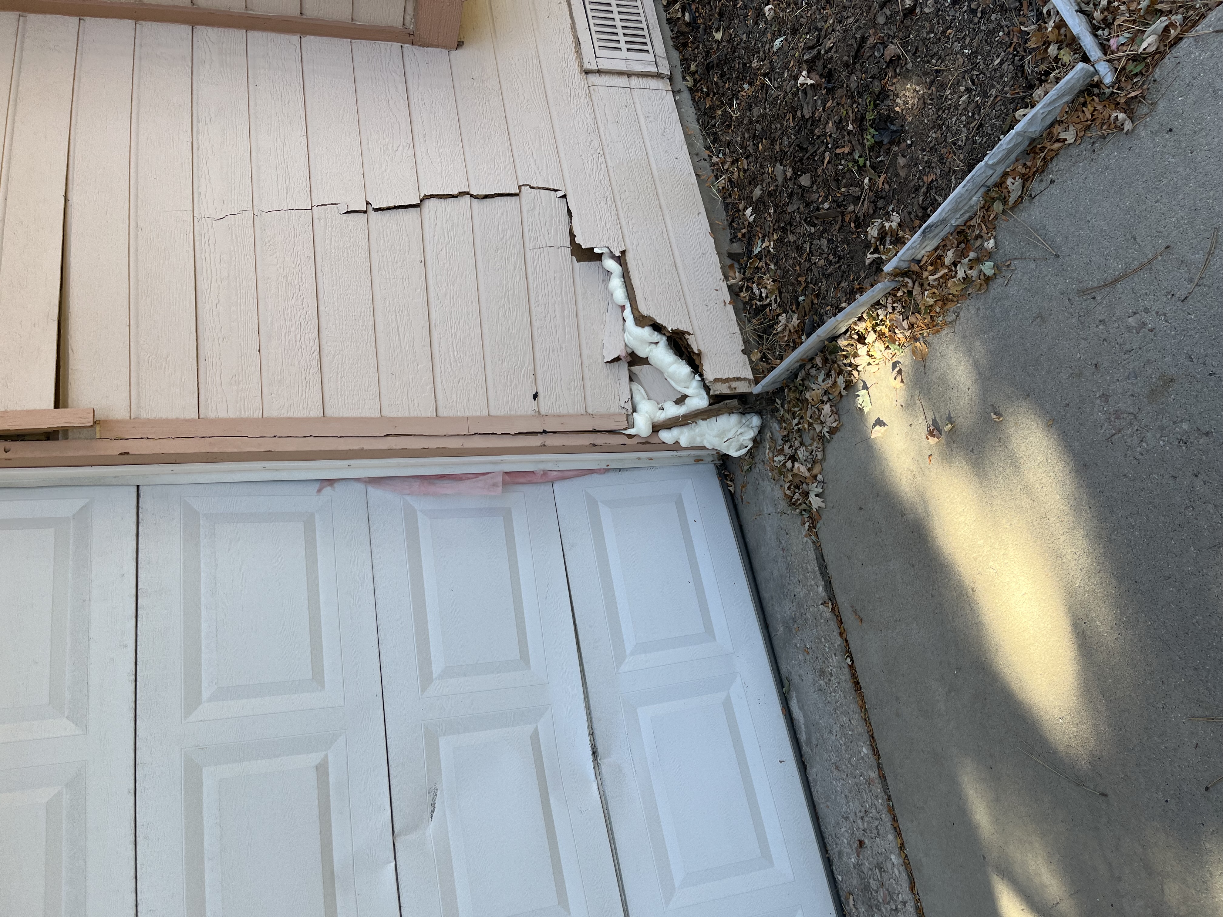 Crack in the siding and garage door damage